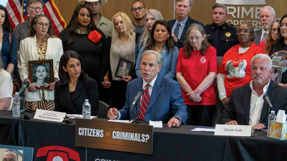 Family and friends of persons who died as a result of violent crime stand behind as Governor Greg Abbott comments on legislation aimed at reducing violent crime during a press conference in Houston, Wednesday, April 30, 2025.