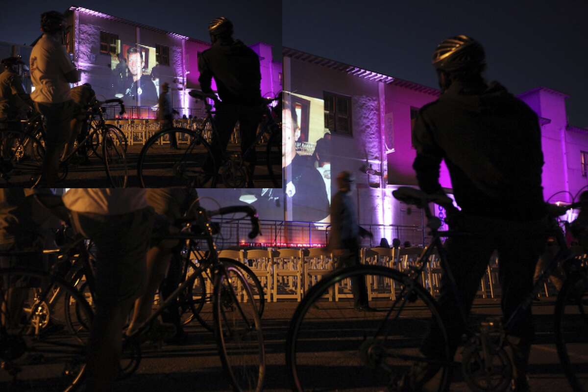 Cyclists watch a slide show of San Antonio artist Chuck Ramirez at Blue Star Art Complex.