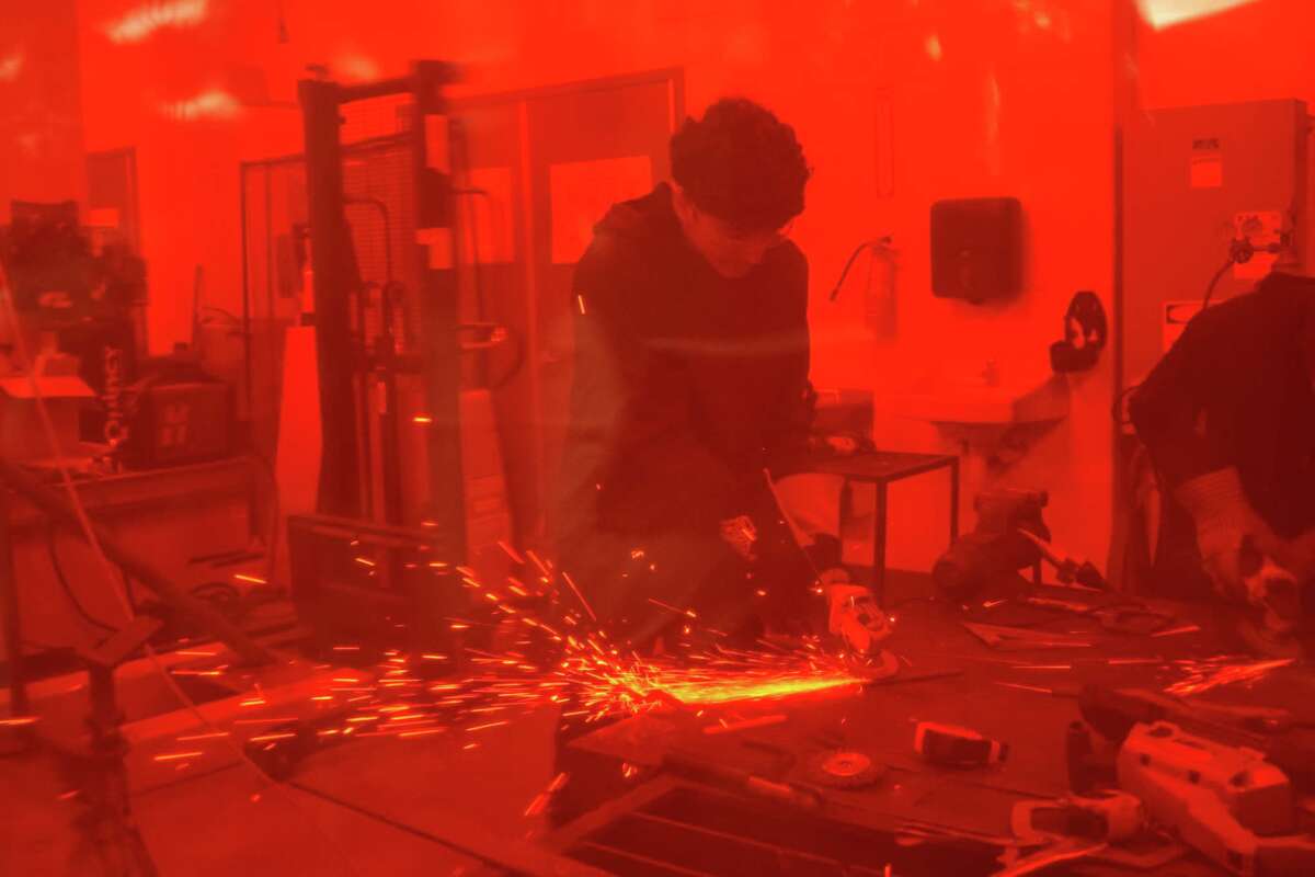 Milby High School students participate in a welding class, seen through a protective screen, on Tuesday, Jan. 28, 2025 in Houston.