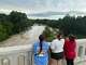 People observing the Comal River after severe storms on June 12, 2025.