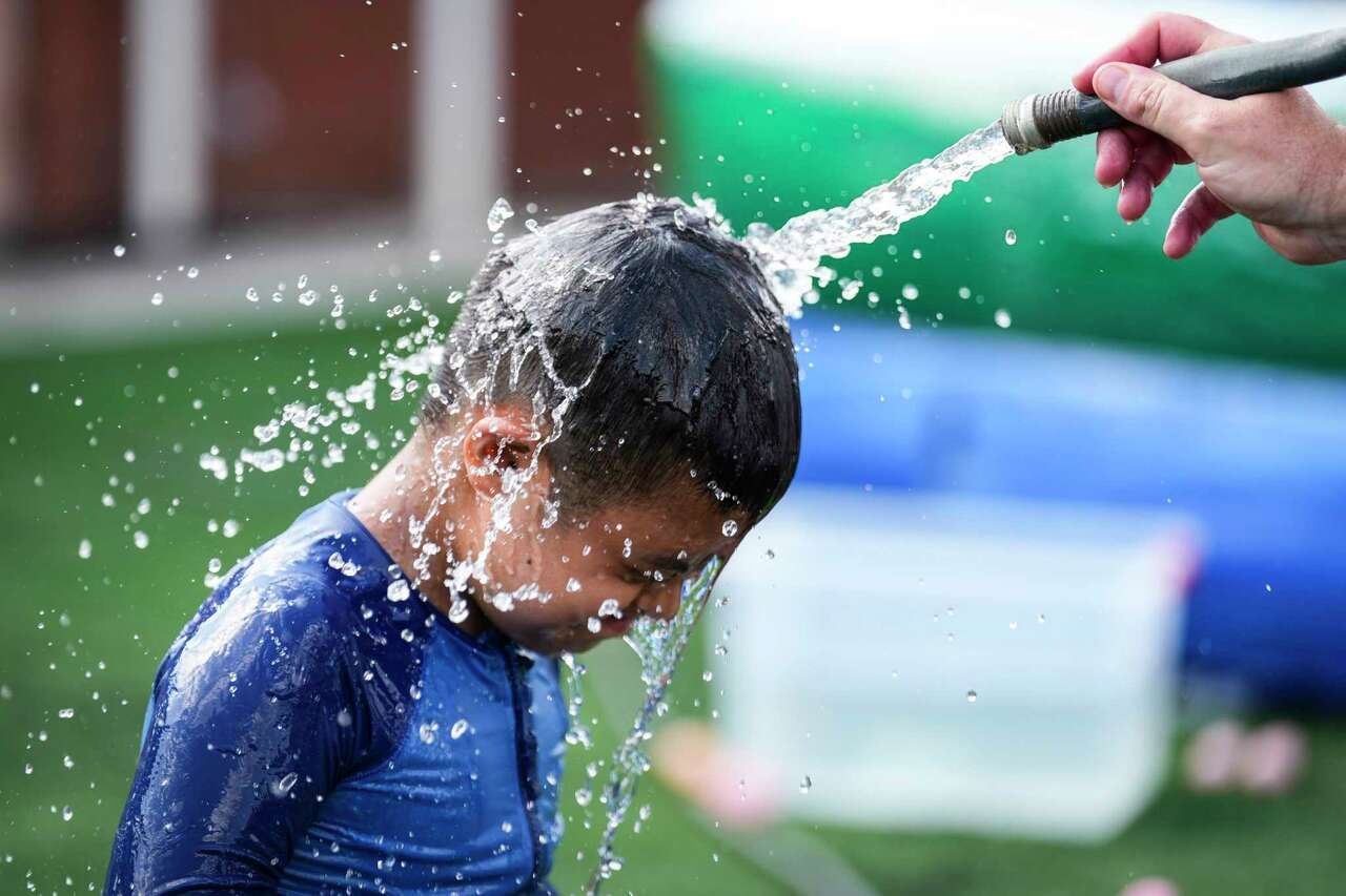 A camper named Dante has water sprayed on his face as he plays with fellow campers during