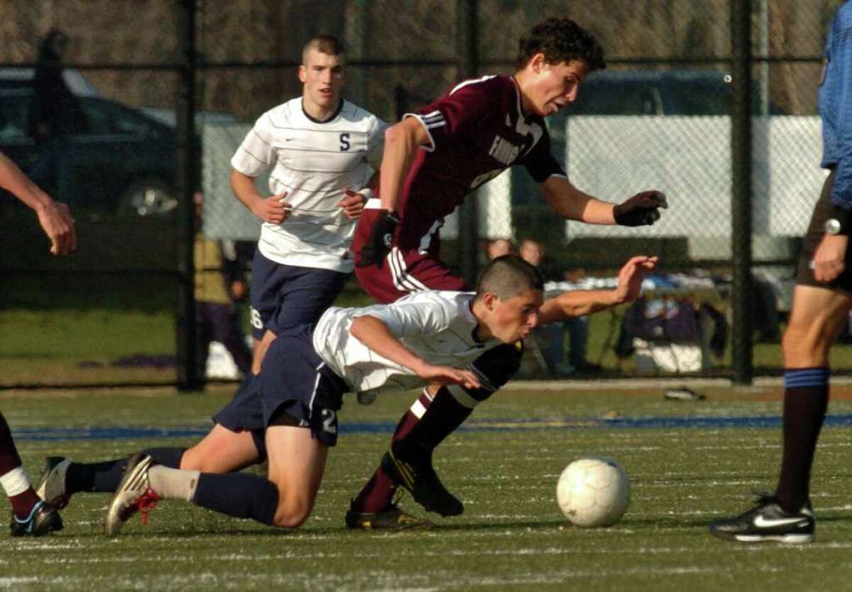 Staples #2 Court Lake takes a spill as he chases down the ball with Farmingham's #6 Kevin Michalak, during the 2010 Boys Soccer State Tournament Class LL final in Waterbury, Conn. on Saturday November 20, 2010. Staples lost to Farmington 2-1.