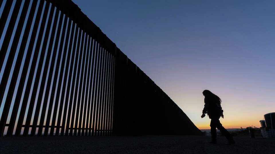 FILE - A volunteer walks along a road next to the border wall separating Mexico and the United States in Jacumba Hot Springs, Calif., Jan. 19, 2025.