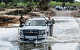 A Wilson County Sheriff’s vehicle escorts two first responders involved in search and rescue across a flooded Center Point River Road just North of Center Point, Texas on July 8, 2025. Tuesday was the first day where rain wasn’t persistent allowing water levels in the Guadalupe River to drop.