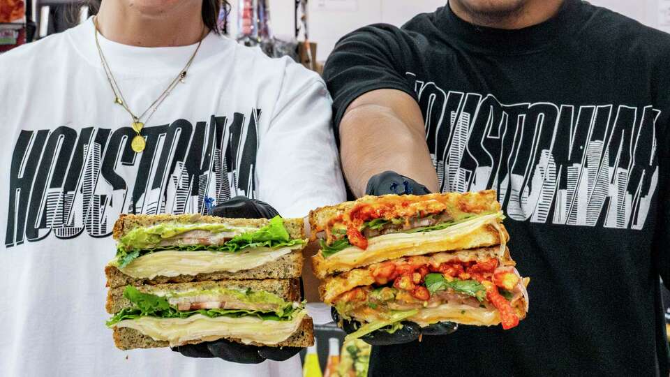 Douglas Flores, left, and Robert Flores, right, hold an original Houstonian sandwich and a Spicy Houstonian sandwich at World Famous Second Slice Sandwich Shop inside Ironworks HTX in Houston, Tuesday, July 8, 2025.