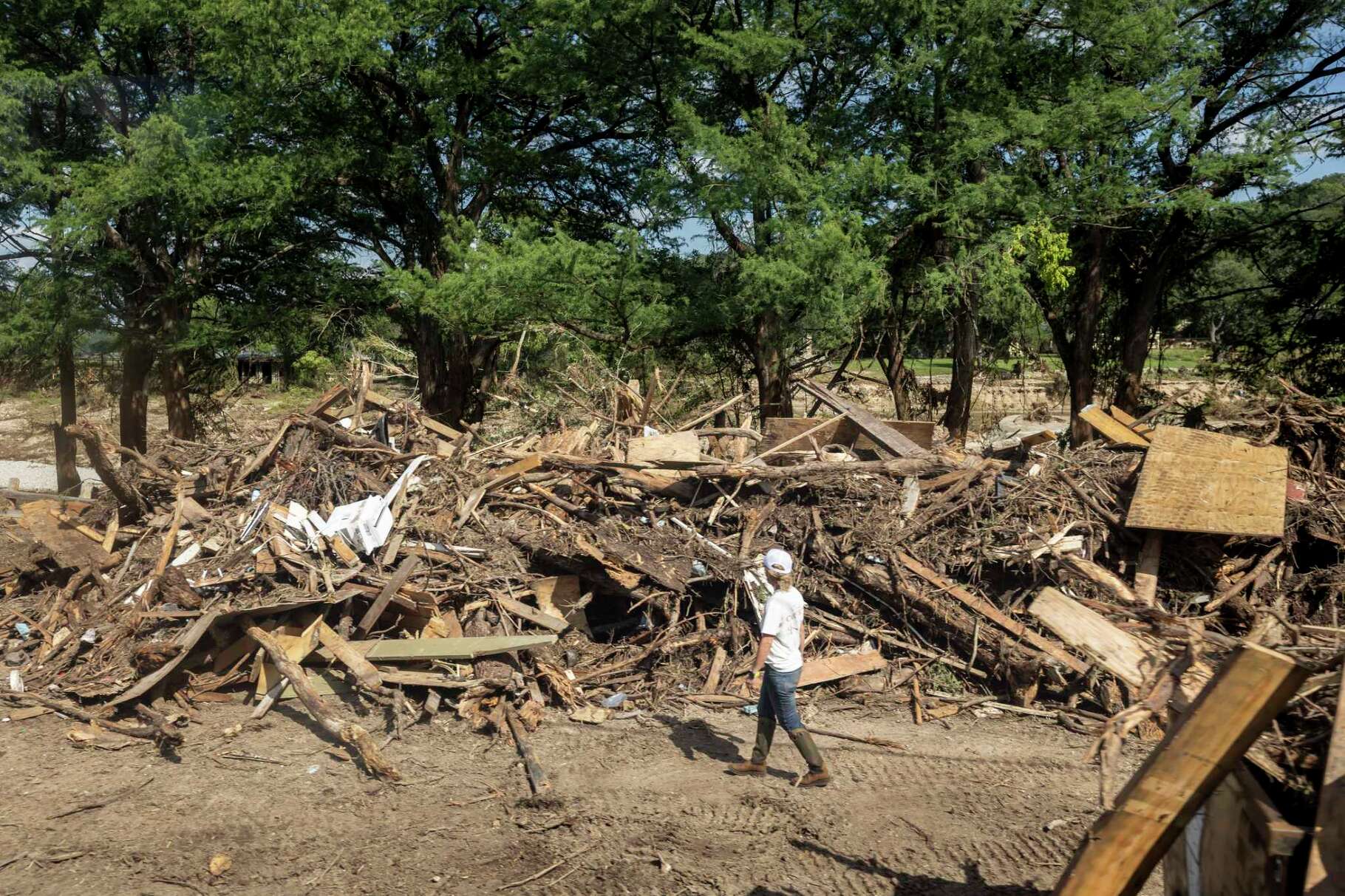 A woman surveys the pile of debris left over from cleaning up from July 4 flooding in Hunt, on Tuesday, July 8, 2025.