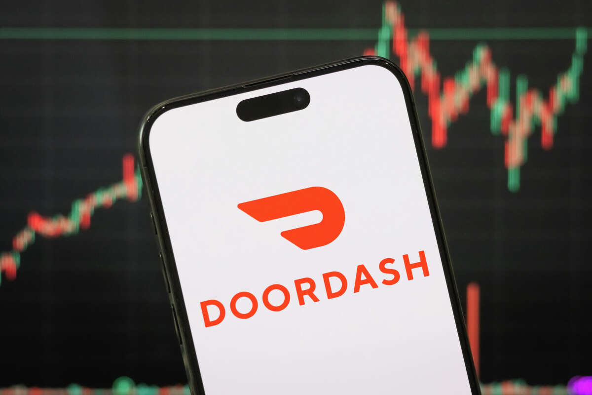 CHONGQING, CHINA - MAY 04: In this photo illustration, the logo of DoorDash, Inc. is displayed on a smartphone screen with a stock market chart in the background reflecting recent financial activity, on May 04, 2025, in Chongqing, China. DoorDash is a United States-based technology company that operates a food delivery platform, connecting customers with local restaurants and convenience services. (Photo illustration by Cheng Xin/Getty Images)