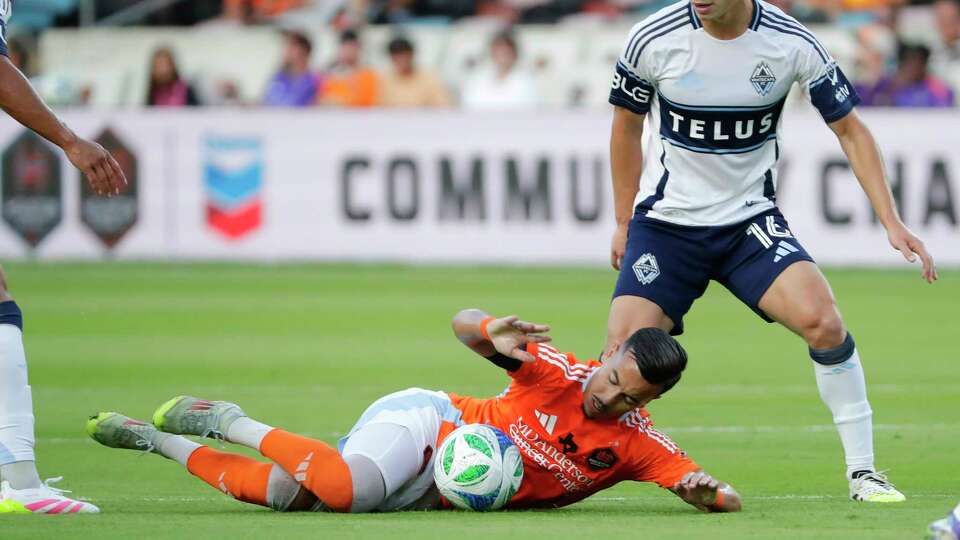 Houston Dynamo midfielder Amine Bassi, bottom, avoids a hand ball after tripping in front of Vancouver Whitecaps midfielder Sebastian Berhalter (16) during the first half of an MLS soccer match, Wednesday, July 16, 2025, in Houston. (AP Photo/Michael Wyke)