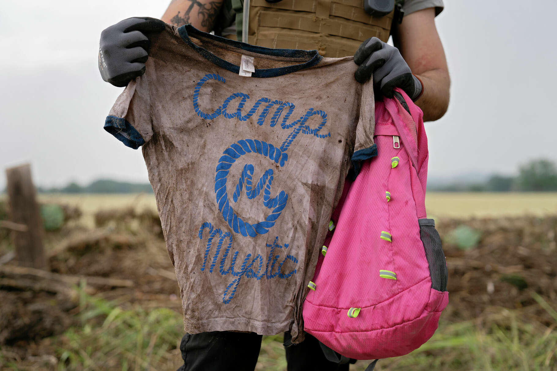 COMFORT, TEXAS - JULY 6: A search and rescue volunteer holds a T-shirt and backpack with the words Camp Mystic on them in Comfort, Texas on July 6, 2025. The volunteer found the belongings yesterday along the Guadalupe River near Ingram, Texas. 'I hope I find the person to return their belongings, not to find closure,' he said. (Photo by Danielle Villasana for The Washington Post via Getty Images)