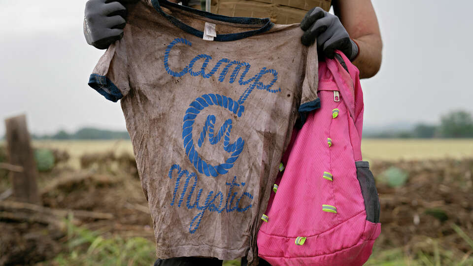 COMFORT, TEXAS - JULY 6: A search and rescue volunteer holds a T-shirt and backpack with the words Camp Mystic on them in Comfort, Texas on July 6, 2025. The volunteer found the belongings yesterday along the Guadalupe River near Ingram, Texas. 'I hope I find the person to return their belongings, not to find closure,' he said. (Photo by Danielle Villasana for The Washington Post via Getty Images)