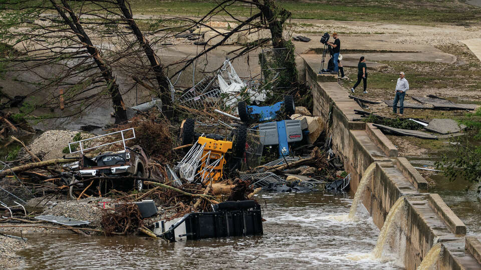 Onlookers and news crews survey the damage from floodwaters near Louise Hays Park along the Guadalupe River in downtown Kerrville, Texas, July 5, 2025.
