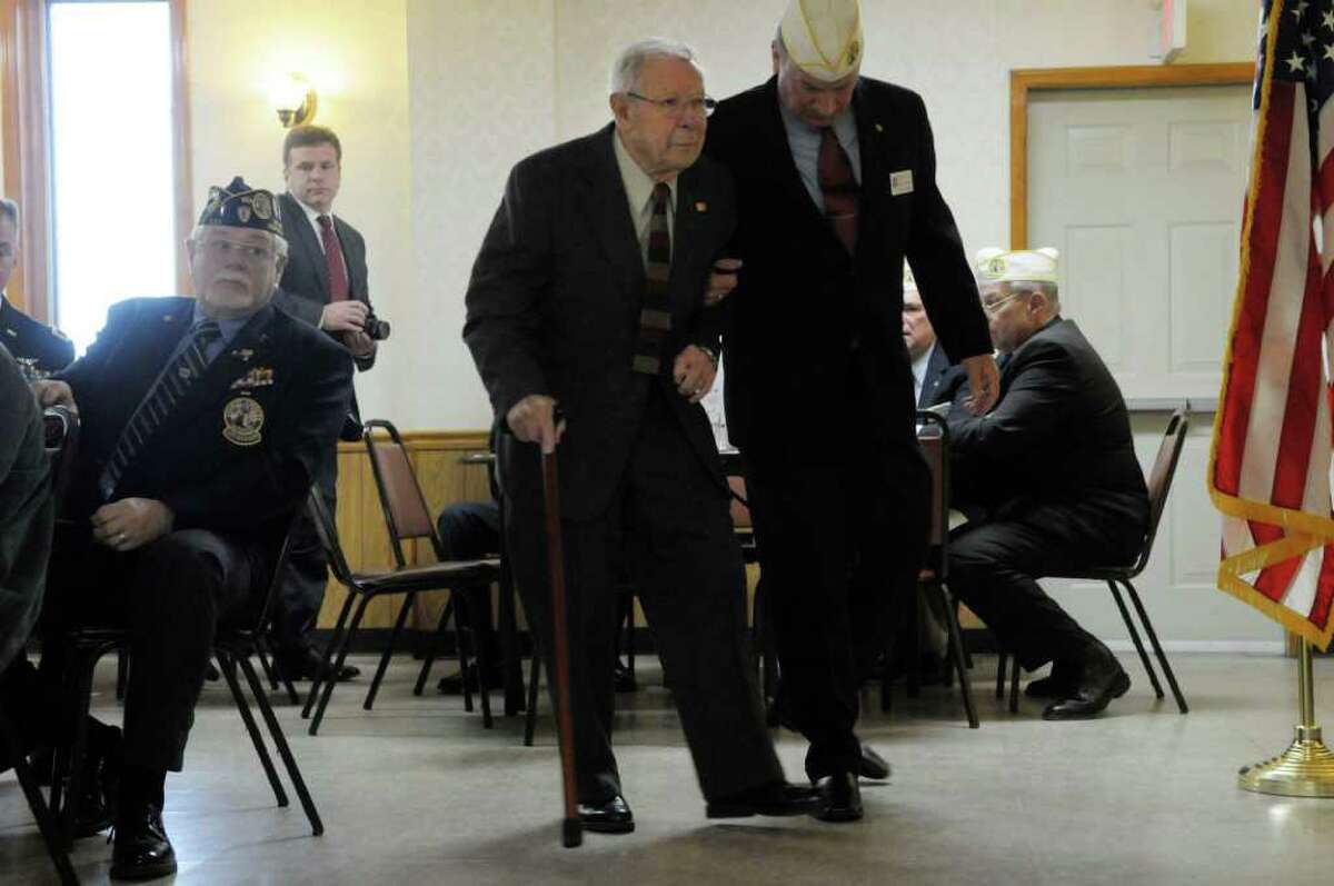 World War II veteran Army Cpl. Sheldon Jones, left, is helped to the podium by Thomas Reiter II, junior vice commander of the Disabled American Veterans Department of New York during a ceremony Sunday at the Veterans of Lansingburgh in Troy. Jones received the Bronze Star Medal for Merit and his Combat Infantry Badge. (Paul Buckowski / Times Union)