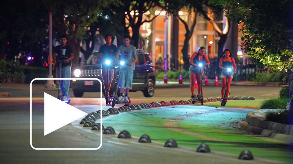 People ride e-scooters on downtown streets in Houston, Texas on Friday July 26, 2025. Mayor John Whitmire’s administration has proposed an outright ban on e-scooters in downtown and surrounding neighborhoods.