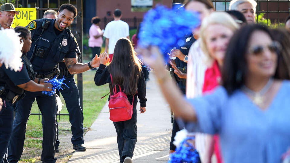 Houston Police Officer Cody Thomas fist bumps students as he joins other community leaders welcoming students back for the first day of school at HISD's Marshall Middle School in Houston, Tuesday, Aug. 12, 2025.