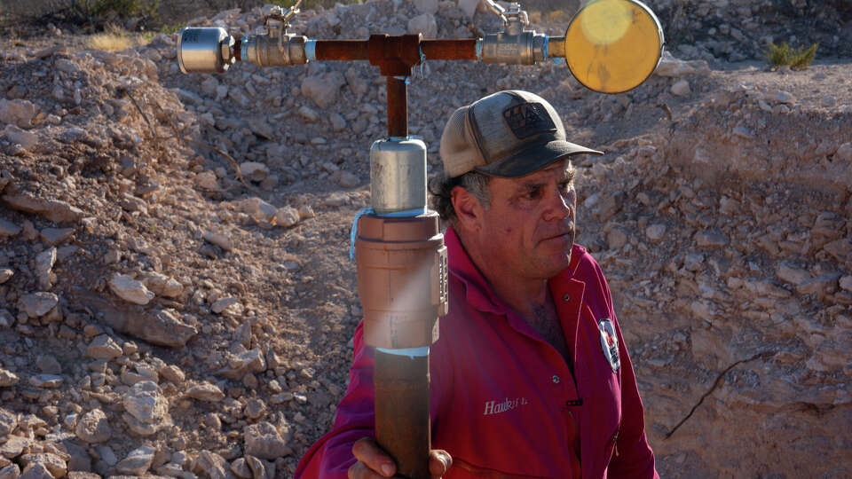 Hawk Dunlap, a veteran oil field worker and well control specialist, holds onto a meter he placed on an abandoned well to measure pressure on Antina Ranch on February 6, 2025 near Monahans, TX.