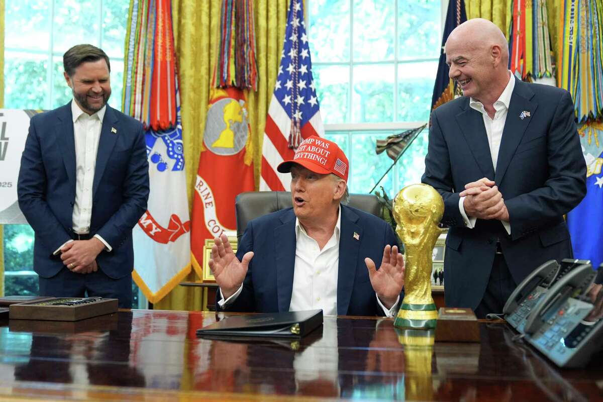 President Donald Trump speaks alongside the FIFA World Cup Winners Trophy as FIFA President Gianni Infantino, right, and Vice President JD Vance watch, during an announcement in the Oval Office of the White House, Friday, Aug. 22, 2025, in Washington. (AP Photo/Jacquelyn Martin)