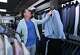 Owner Kelly Fagan hangs an Italian jacket at Mark Thomas Men's Apparel in Colony in September 2025. Fagan uses the free version of ChatGPT multiple times a day in his store for a variety of tasks, including website improvement recommendations, social media posts, and mortgage financing scenarios.