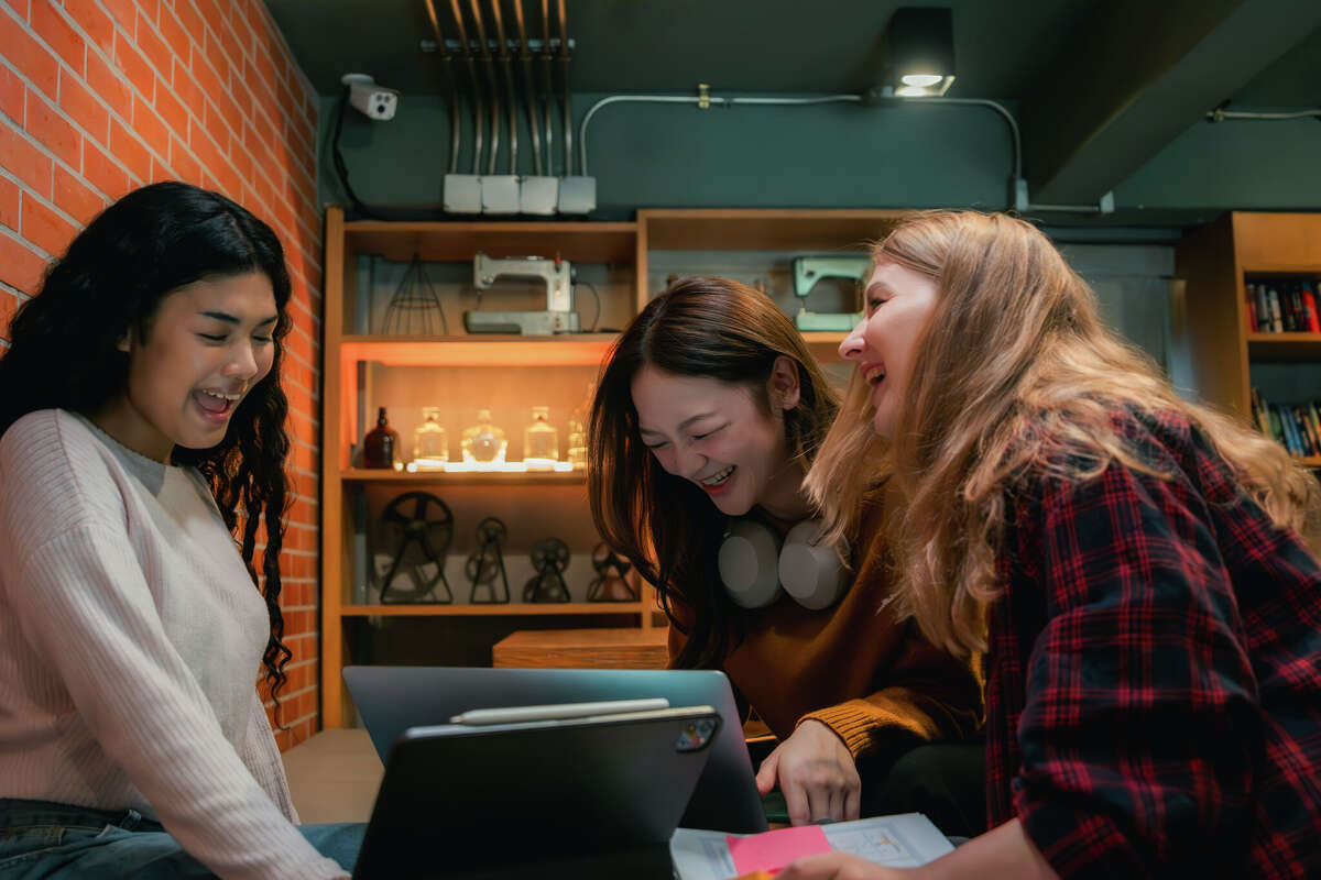 Supportive friends helping their roommate study for an exam at night in the dormitory, offering notes, encouragement, and motivation, with a reassuring pat on the shoulder and a heartfelt 'You got this' to keep spirits and energy high