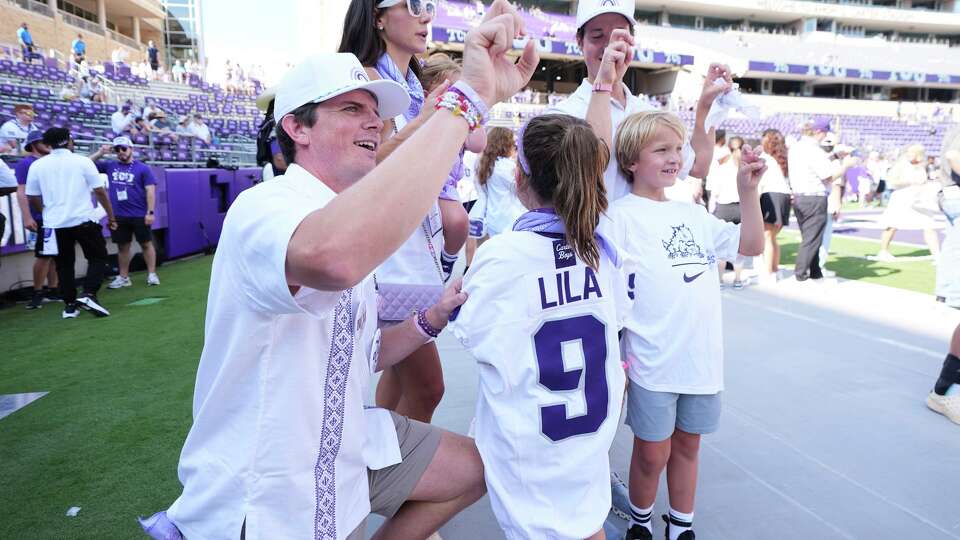 Blake Bonner, left, his wife Caitlin, left rear, standing and their daughter, front, wearing a shirt with her late sisters name stand in the end zone before an NCAA college football game between SMU and TCU, Saturday, Sept. 20, 2025, in Fort Worth, Texas.