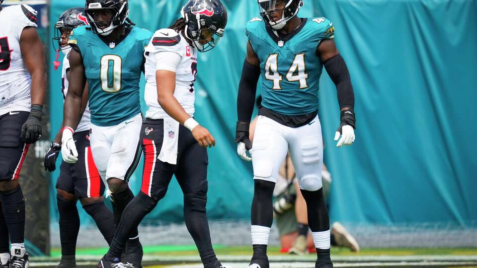 Houston Texans quarterback CJ. Stroud (7) walks off the field between Jacksonville Jaguars linebacker Devin Lloyd (0) and defensive end Travon Walker (44) after he was sacked during the first half of an NFL football game at Everbank Stadium in Jacksonvillew, Fla., Sunday, Sept. 21, 2025.
