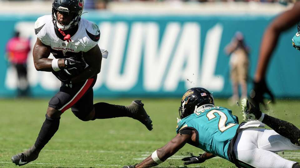Houston Texans running back Woody Marks (27) runs the ball past Jacksonville Jaguars cornerback Jourdan Lewis (2) during the second half of an NFL football game at Everbank Stadium in Jacksonville, Fla., Sunday, Sept. 21, 2025.