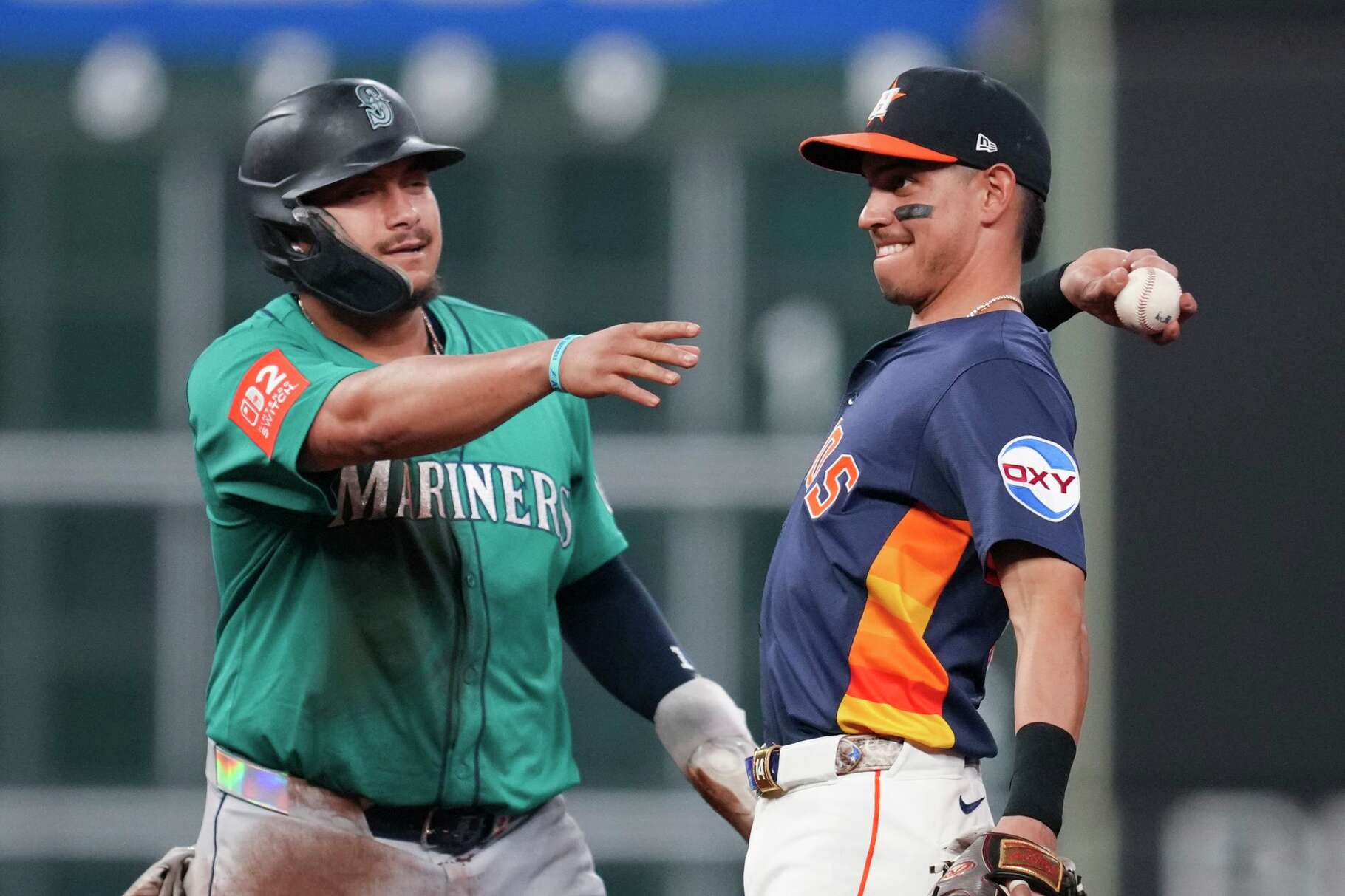 Seattle Mariners Josh Naylor (12) tries to mess with a throw by Houston Astros shortstop Mauricio Dubón (14) back to catcher Yainer Diaz after Dubón tried to fake Naylor out to step off the bag during the eighth inning of a MLB baseball game in Houston, Sunday, Sept. 21, 2025.