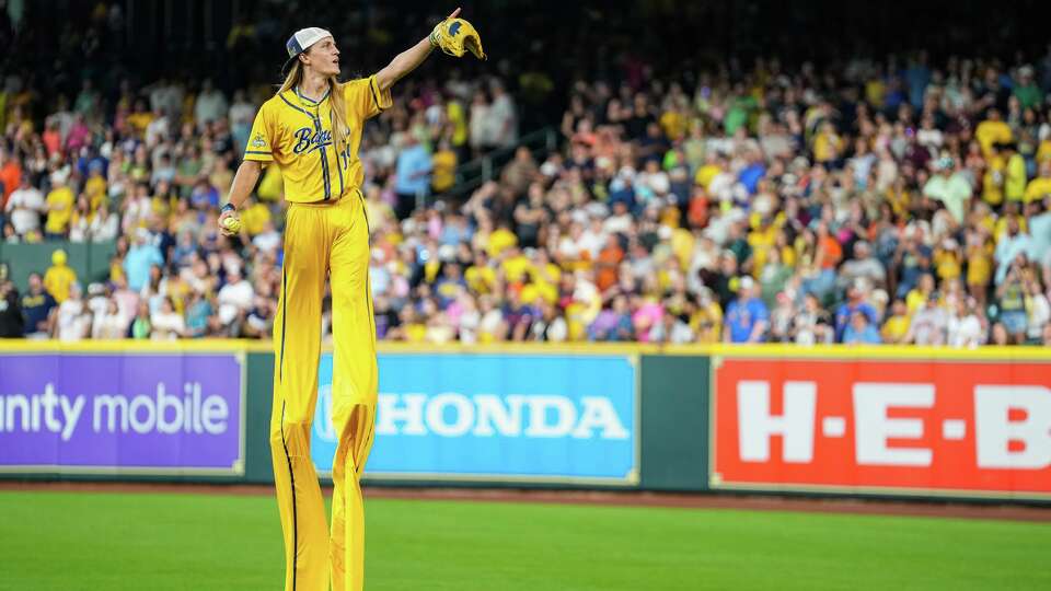 Savannah Bananas player on stilts throws a ball to the crowd before playing against the Texas Tailgaters at Daikin Park on Saturday, Sept. 27, 2025 in Houston.