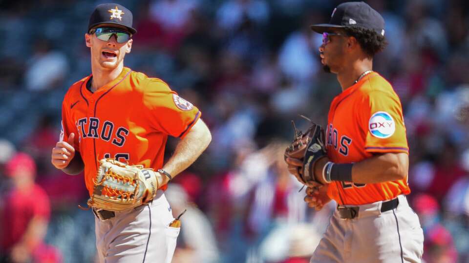 Houston Astros left fielder Zach Cole, left, talks with second baseman Brice Matthews as they jog from the dugout during an MLB baseball game in Anaheim, Sunday, Sept. 28, 2025.