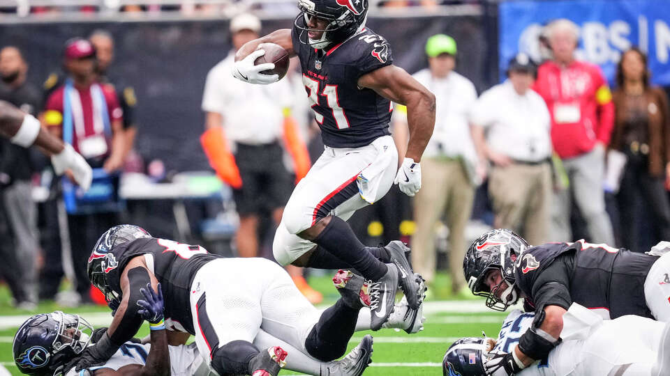 Houston Texans running back Nick Chubb (21) leaps through a hole in the Tennessee Titans defense during the second half of an NFL football game at NRG Stadium in Houston, Sunday, Sept. 28, 2025.