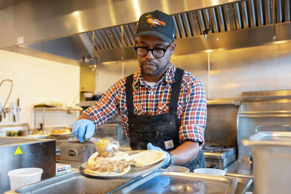Chef Ryan Grimes spoons jerk chicken onto tortillas at Third Place.