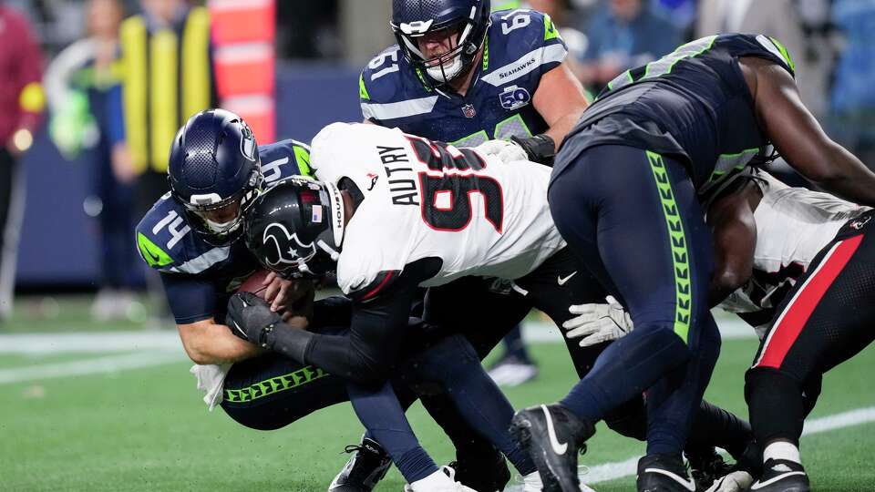 Houston Texans defensive end Denico Autry (99) tackles Seattle Seahawks quarterback Sam Darnold (14) during the second half of an NFL football game, Tuesday, Oct. 21, 2025, in Seattle.