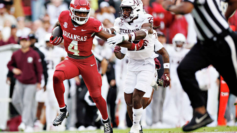 FAYETTEVILLE, ARKANSAS - OCTOBER 18: Mike Washington Jr. #4 of the Arkansas Razorbacks runs the ball in the first half and is chased by Dalton Brooks #25 of the Texas A&M Aggies at Donald W. Reynolds Razorback Stadium on October 18, 2025 in Fayetteville, Ark. (Photo by Wesley Hitt/Getty Images)