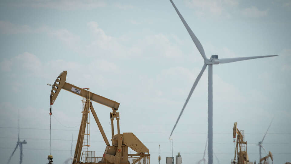 Pumpjacks operate next to large wind turbines Friday, July 8, 2022, near Midland.