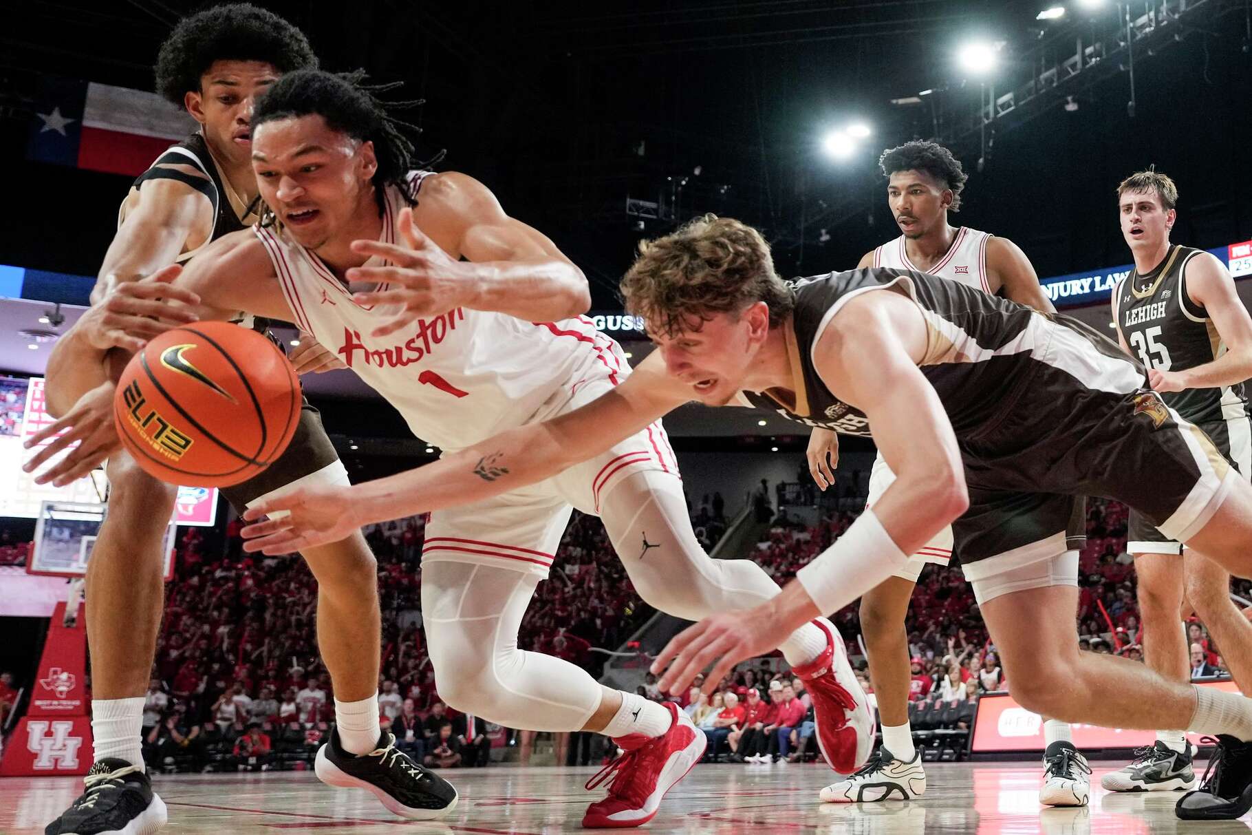 Houston guard Isiah Harwell (1) and Lehigh forward Edouard Benoit (5) got after a loose ball during the second half of an NCAA college basketball game at Fertitta Center in Houston, Monday, Nov. 3, 2025.