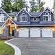 Luxury house with three-car garage, concrete driveway and blue vinyl siding.