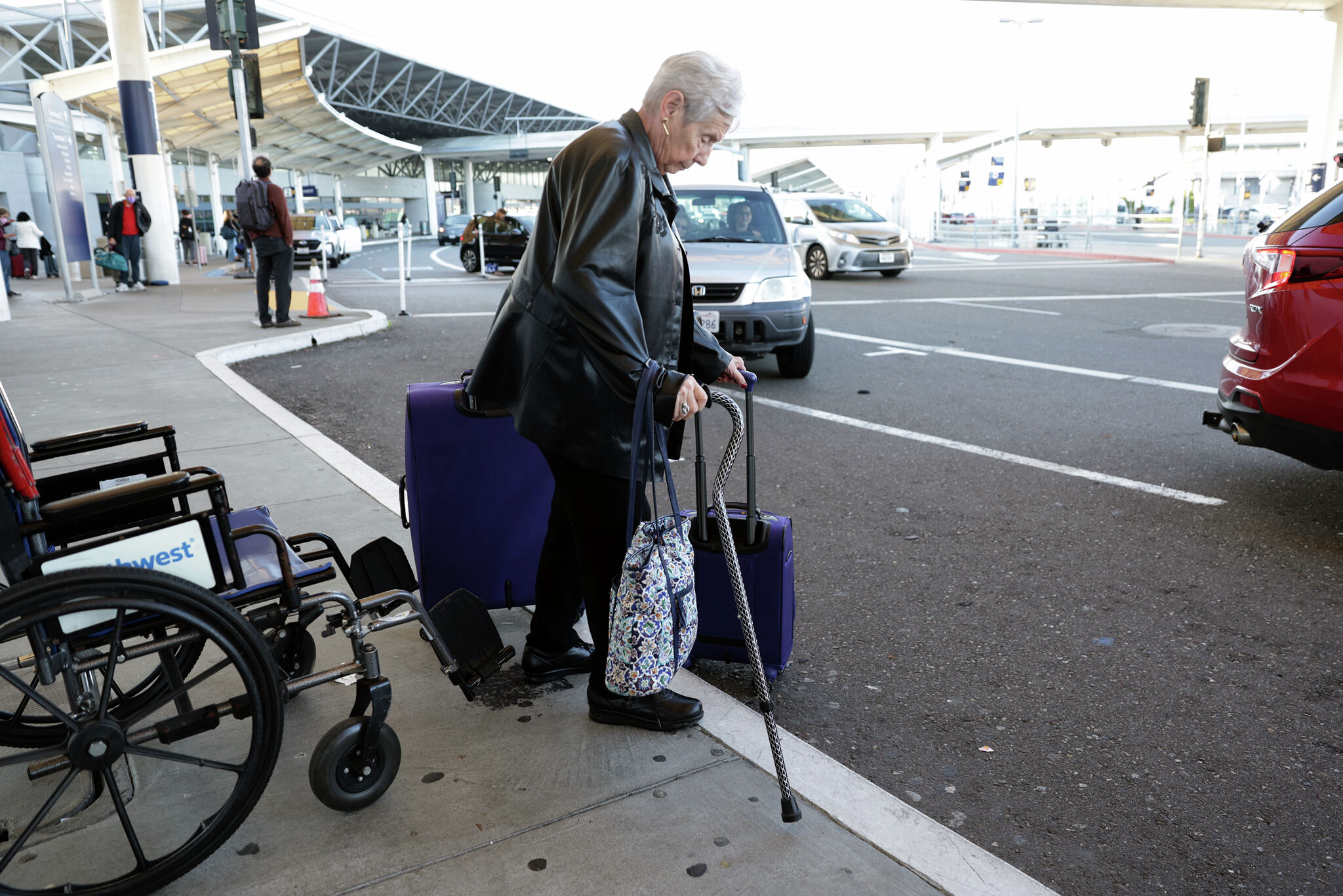 An older traveler walking through an airport terminal toward a pickup area