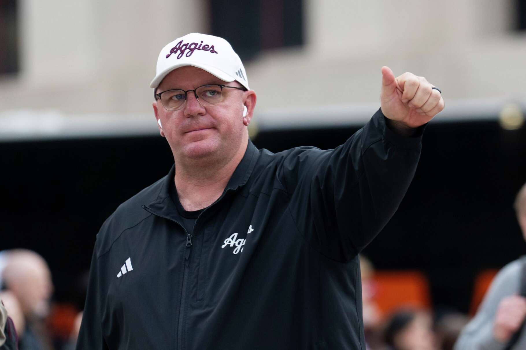 Texas A&M head coach Mike Elko signals to fans as the team busses arrive before an NCAA college football game in Austin, Friday, Nov. 28, 2025.