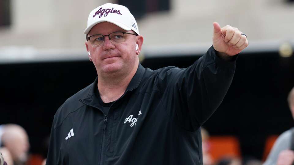 Texas A&M head coach Mike Elko signals to fans as the team busses arrive before an NCAA college football game in Austin, Friday, Nov. 28, 2025.