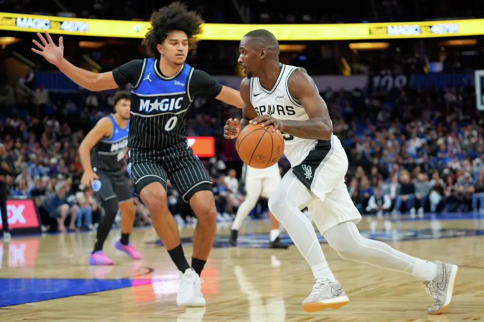 San Antonio Spurs forward David Jones Garcia, right, drives against Orlando Magic guard Anthony Black (0) during the first half of an NBA basketball game, Wednesday, Dec. 3, 2025, in Orlando, Fla. (AP Photo/John Raoux)
