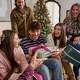 Happy family exchangeing gifts in the livingroom with a tree in the background.