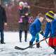 Family playing pond hockey in the snowy park.