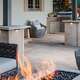 Patio in backyard with pavers outdoor kitchen cozy outdoor furniture and a fire feature.