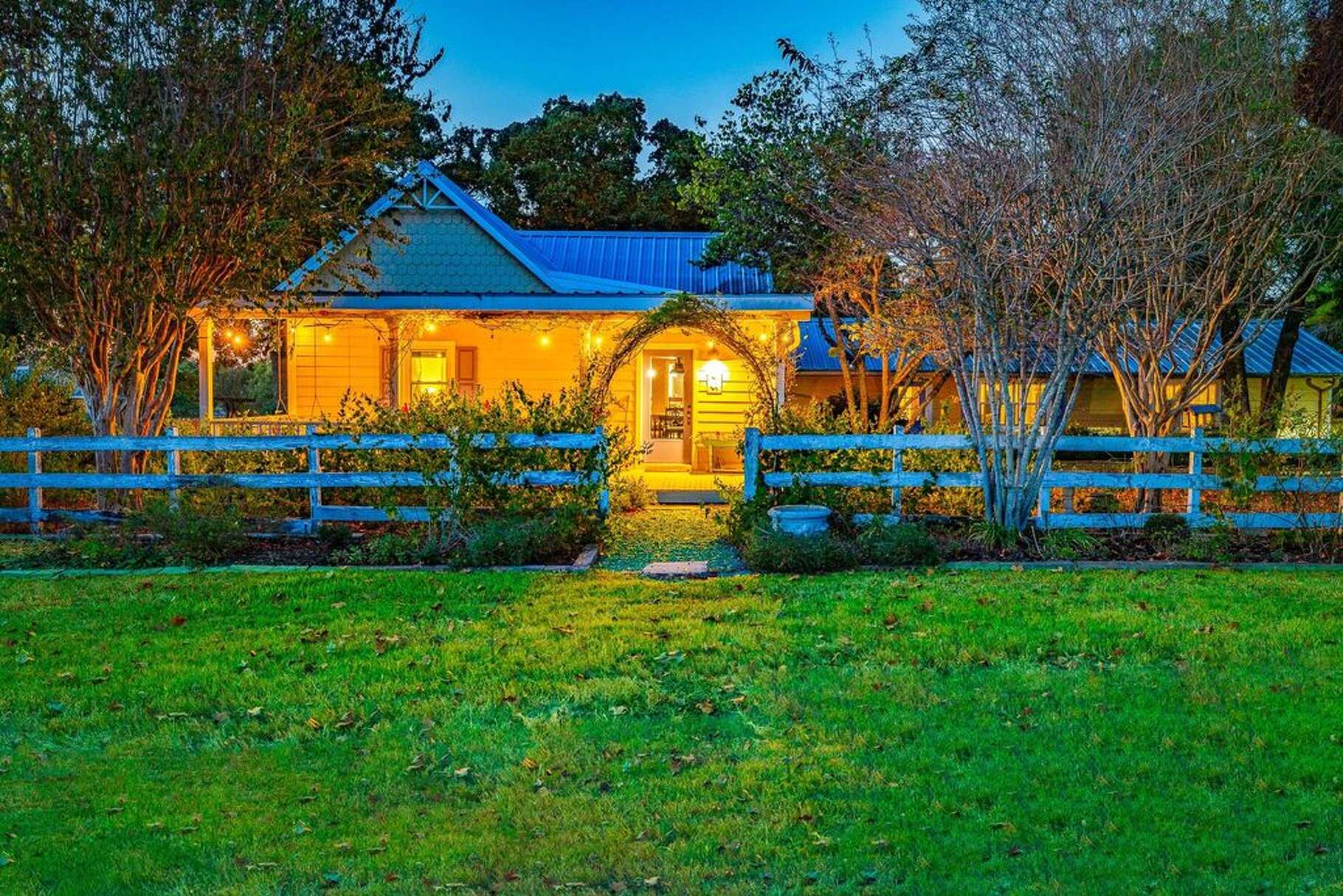 A classic white fence frames the original farmhouse at Suzanne Longley's ranch in Brenham.