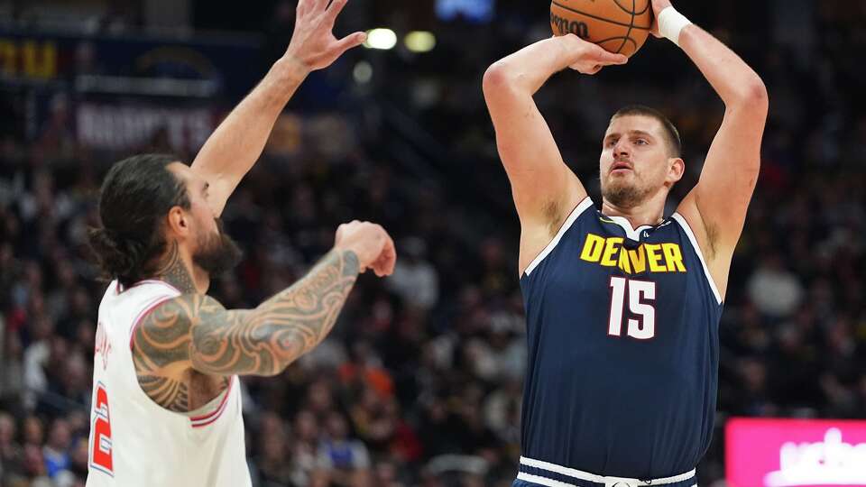 Denver Nuggets center Nikola Jokic, right, looks to shoot a basket over Houston Rockets center Steven Adams, left, in the first half of an NBA basketball game Monday, Dec. 15, 2025, in Denver. (AP Photo/David Zalubowski)