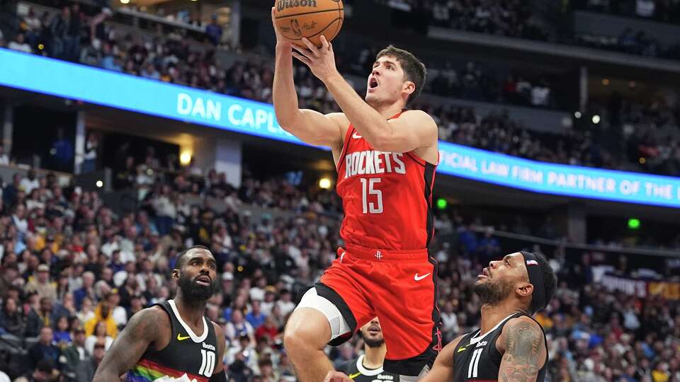 Houston Rockets guard Reed Sheppard, center, drives to the basket between Denver Nuggets guards Tim Hardaway Jr., left, and Bruce Brown, right, in the second half of an NBA basketball game Saturday, Dec. 20, 2025, in Denver. (AP Photo/David Zalubowski)
