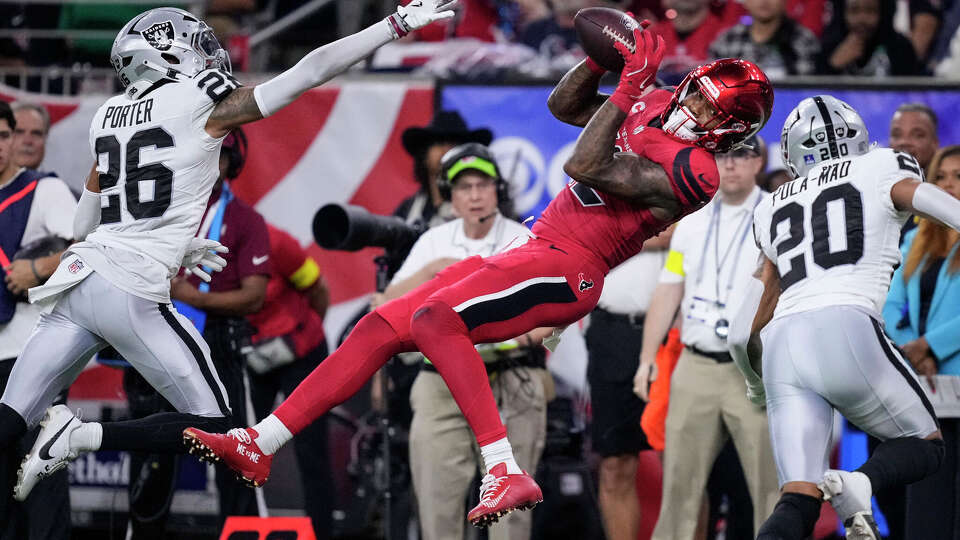 Houston Texans wide receiver Nico Collins (12) leaps between Las Vegas Raiders cornerback Darien Porter (26) and Raiders safety Isaiah Pola-Mao (20) to grab a 24-yard reception for a first down during the second half of an NFL football game at NRG Stadium in Houston, Sunday, Dec. 21, 2025.