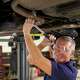 Portrait Of Auto Mechanic Working Underneath Car In Garage