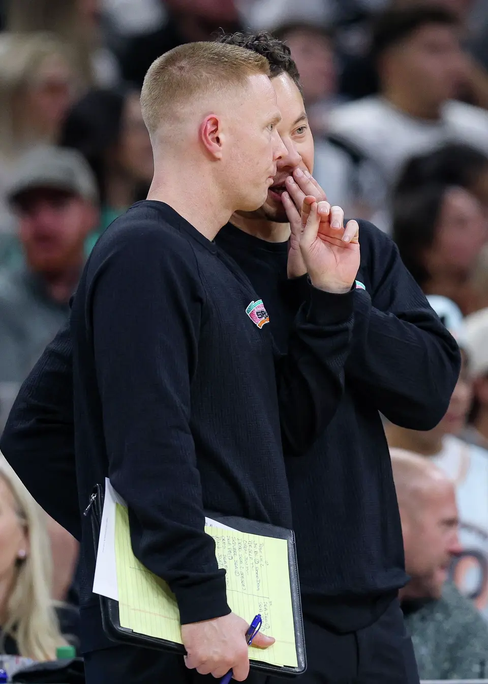 San Antonio Spurs head coach Mitch Johnson, back, talks to associate head coach Sean Sweeney as their team takes on the Oklahoma City Thunder at Frost Bank Center in San Antonio, Tuesday, Dec. 23, 2025. The Spurs defeated the Thunder, 130-110.