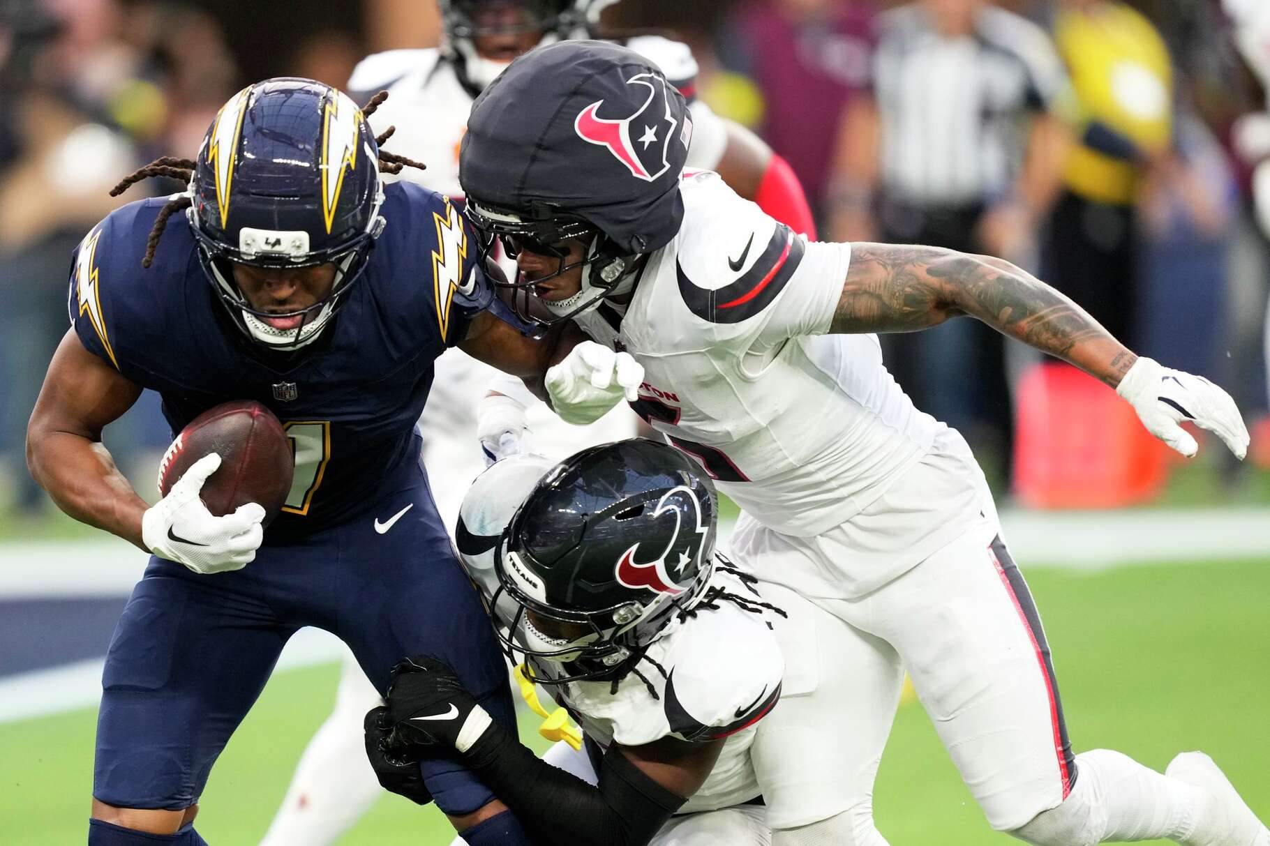 Houston Texans safety Jalen Pitre (5) tackles Los Angeles Chargers wide receiver Quentin Johnston (1) alongside cornerback Kamari Lassiter (4) during the second half of an NFL football game in Inglewood, Calif., Saturday, Dec. 27, 2025.