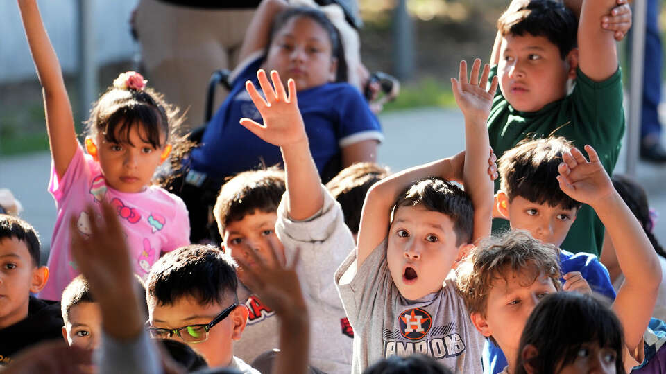 Alex Andre 8, right, and other third graders at Herrera Elementary School raise their hands to ask questions of Mike Foreman, retired astronaut, during his presentation before a launch of rockets made from plastic bottles in Houston Thursday, Oct. 9, 2025. The rockets powered by baking soda and vinegar were launched during the Arm & Hammer Baking Soda Rocket Day a nationwide initiative designed to spark curiosity and creativity in STEAM.
